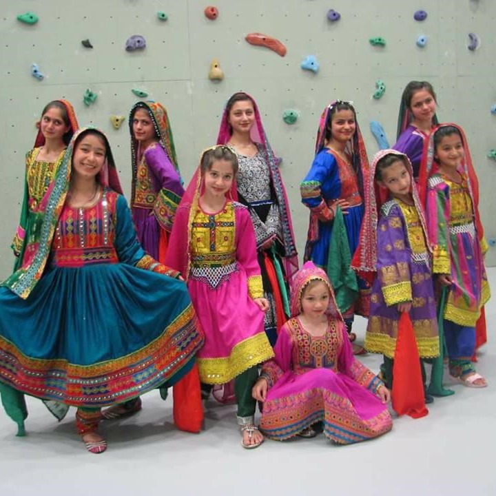 Jovial Afghan girls in traditional costumes at a regional music festival