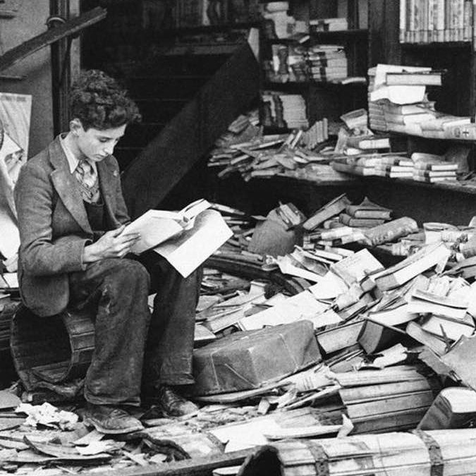 Boy reads The History of London amid the ruins of a London bookshop after an air raid on October 8, 1940