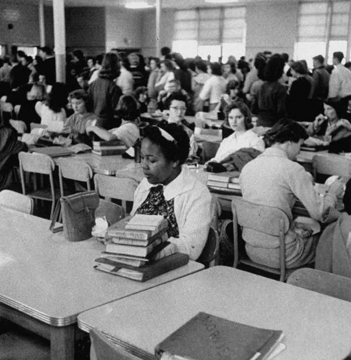 An African-American girl eating lunch alone, after being newly integrated into a high school, 1959