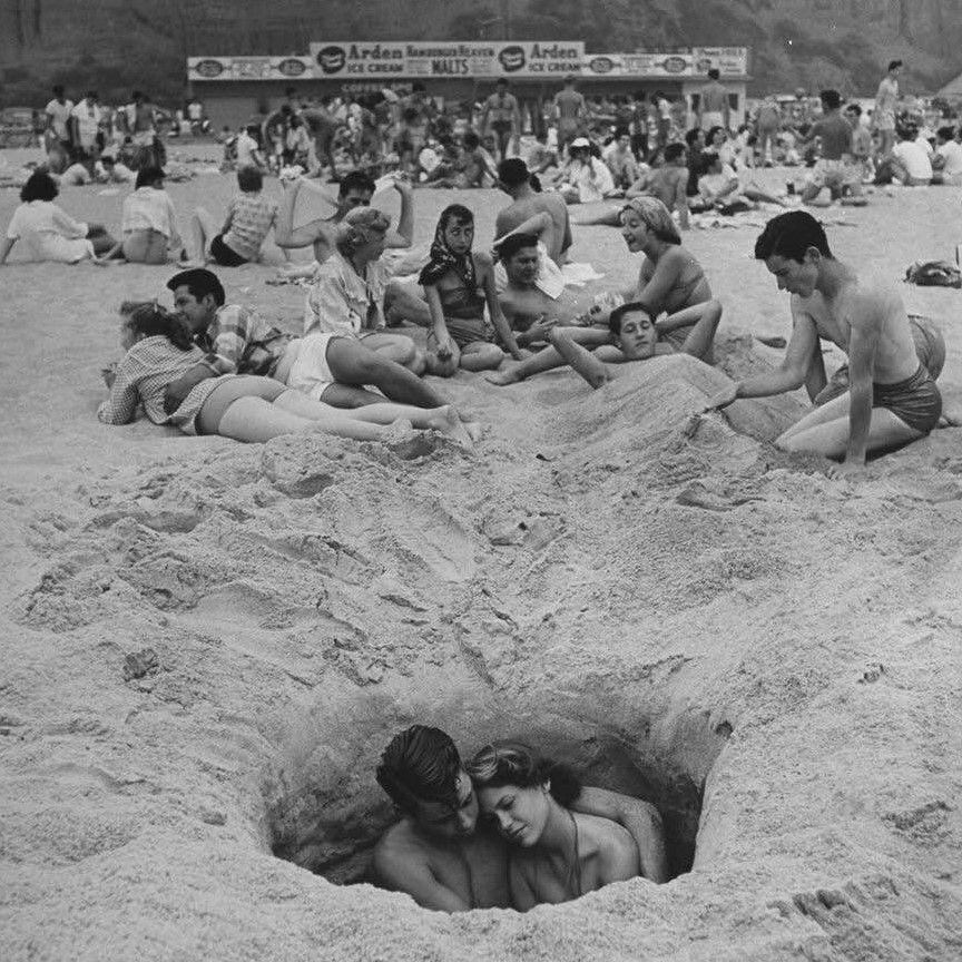 Finding a place to be alone on crowded Santa Monica beach, 1950