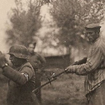 Liberated Jewish prisoner holds one of the German guards at gunpoint
