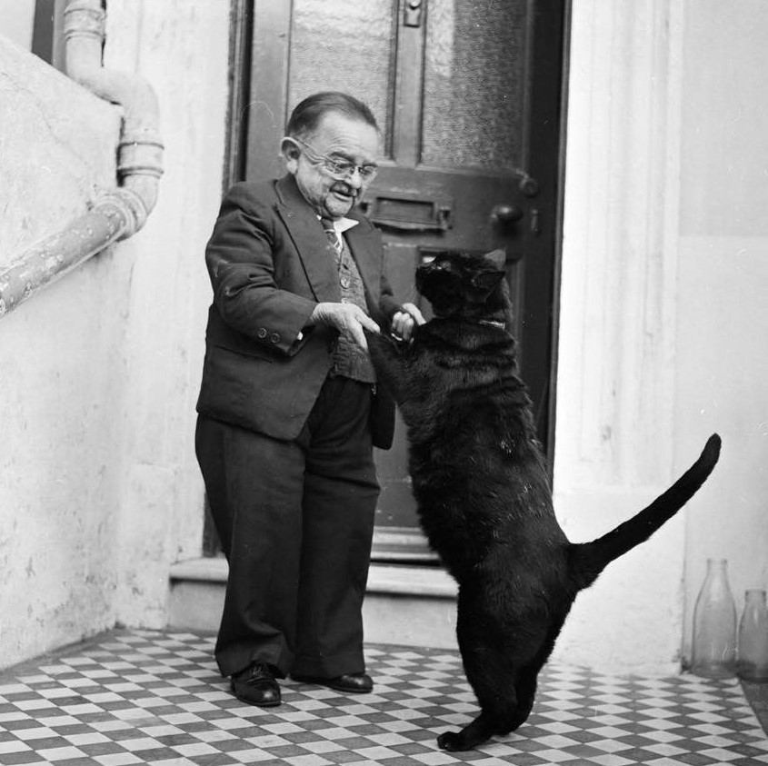 Henry Behrens, the smallest man in the world, dances with his pet cat,1956