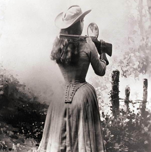 Sharpshooter Annie Oakley using a hand mirror to shoot over her shoulder circa 1899