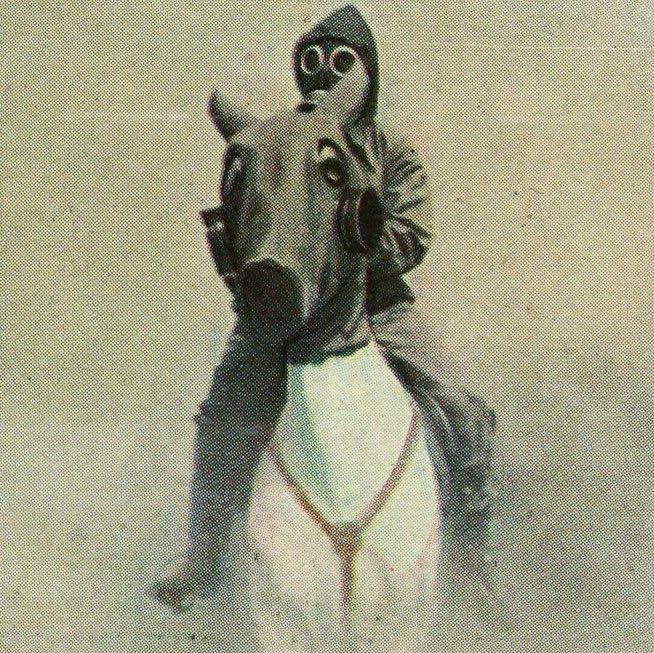 An English cavalryman rides through a gas attack with protective mask and body cover, 1934