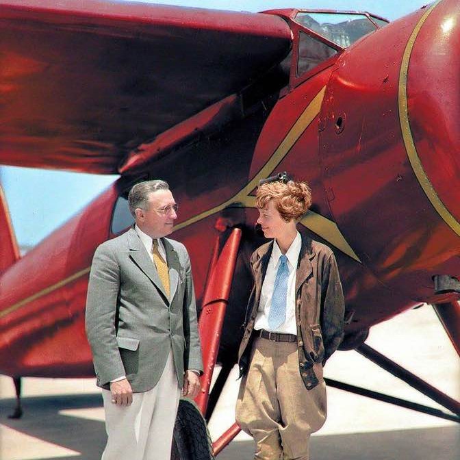Colorized photo of Amelia Earhart standing in front of her single-prop plane in Burbank, California, 1932