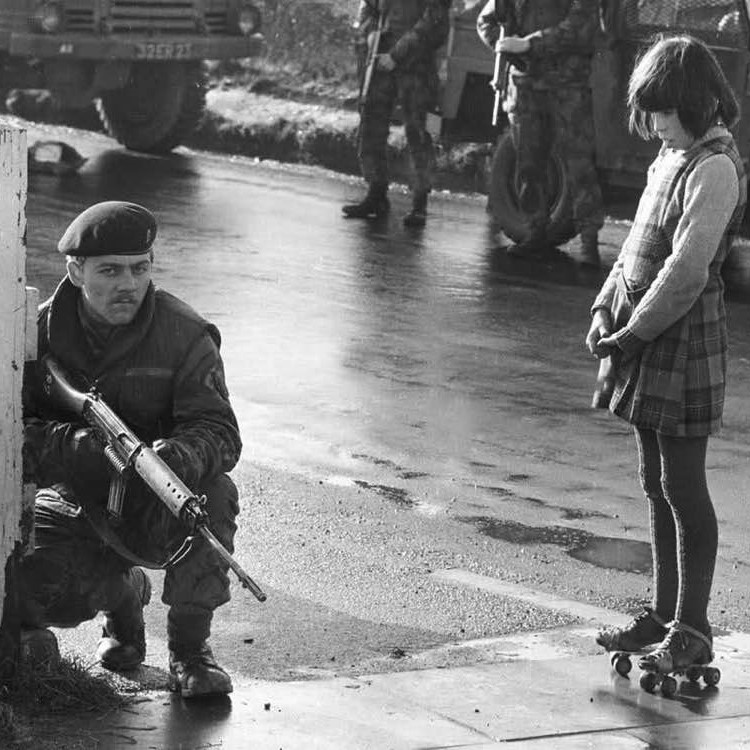 Curious girl on roller-skates watches army patrol during the Battle of the Bogside, Northern Ireland, 1969 (photo by Clive Limpkin)