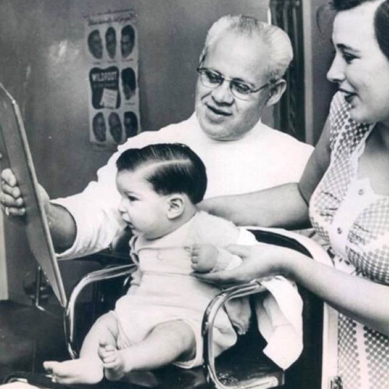 Baby doesn't seem to be pleased after his first haircut, 1955