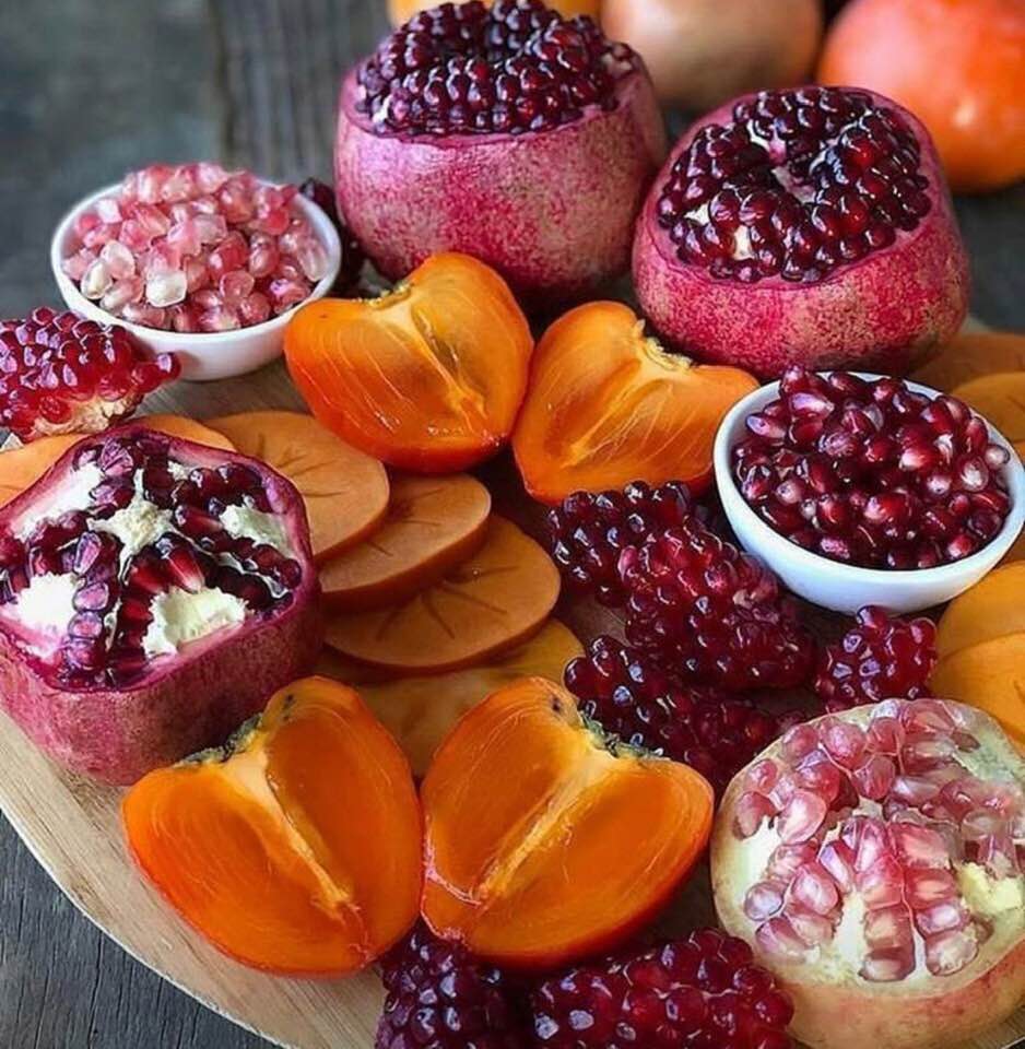 Pomegranates of various colors, and persimmons