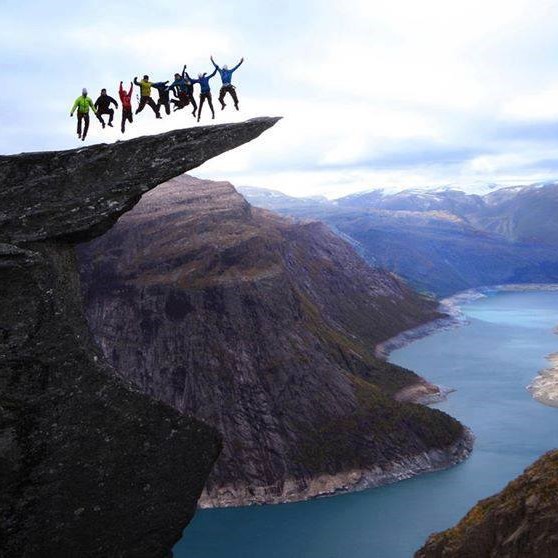 A group of people jumping on a protruding rock