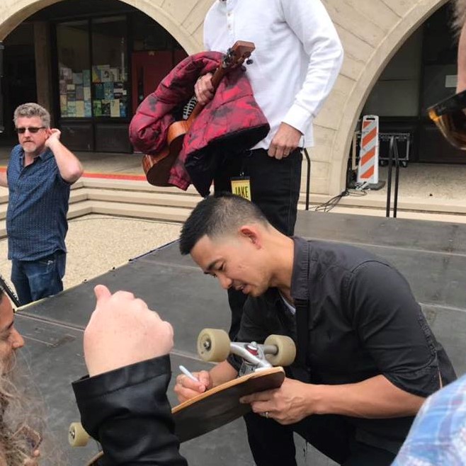 Jake Shimabukuro autographing a skateboard after his performance at UCSB