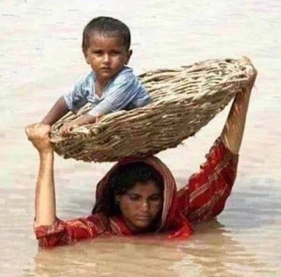 A woman carrying a child in a basket over her head during Iran's recent floods
