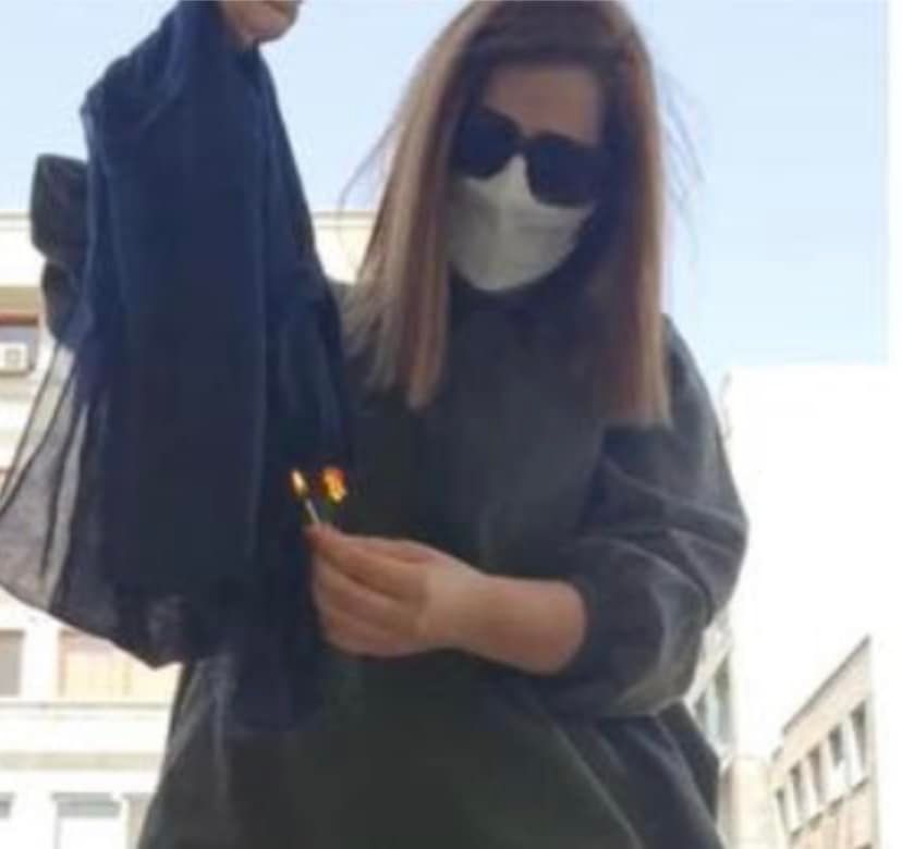 Iranian woman burning her headscarf in protest to mandatory hijab laws