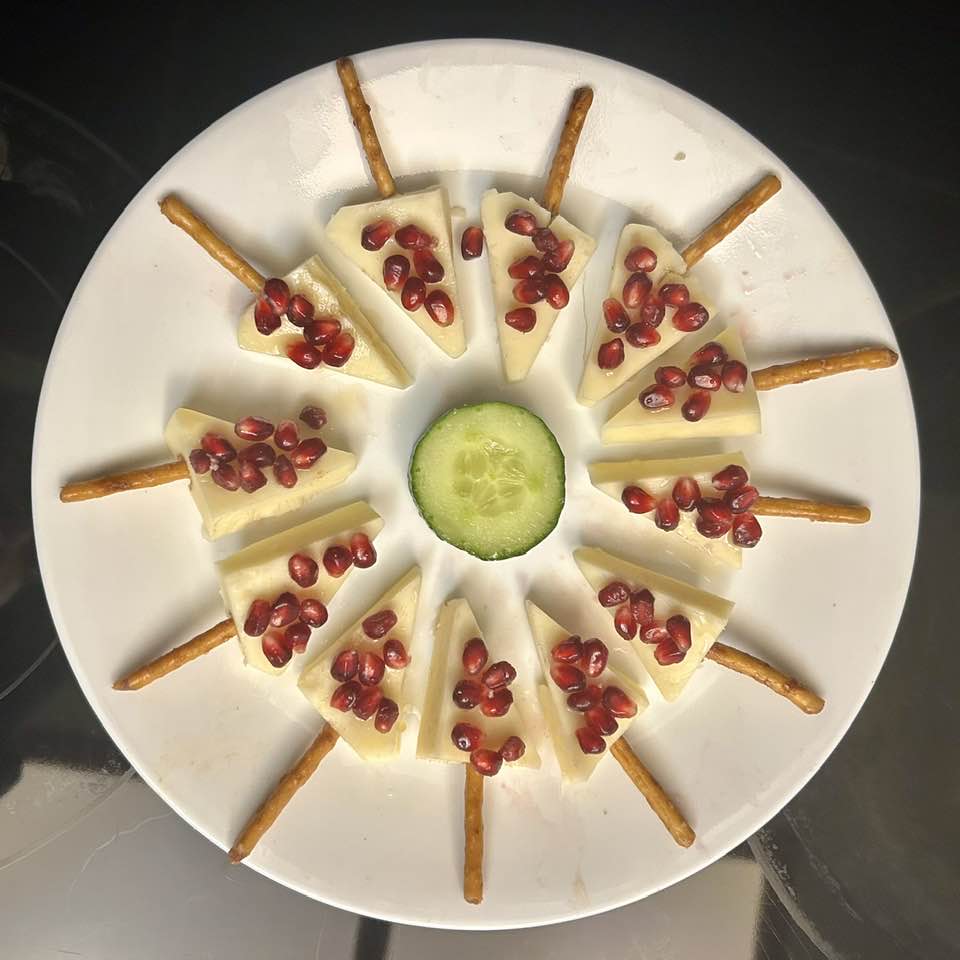 Holiday snacks made of cheese wedges, pretzel sticks, & pomegranates